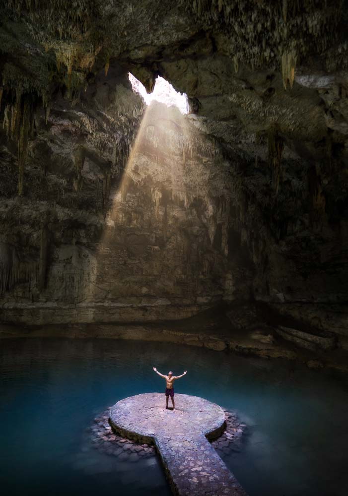 person standing rock cave with sun shining it