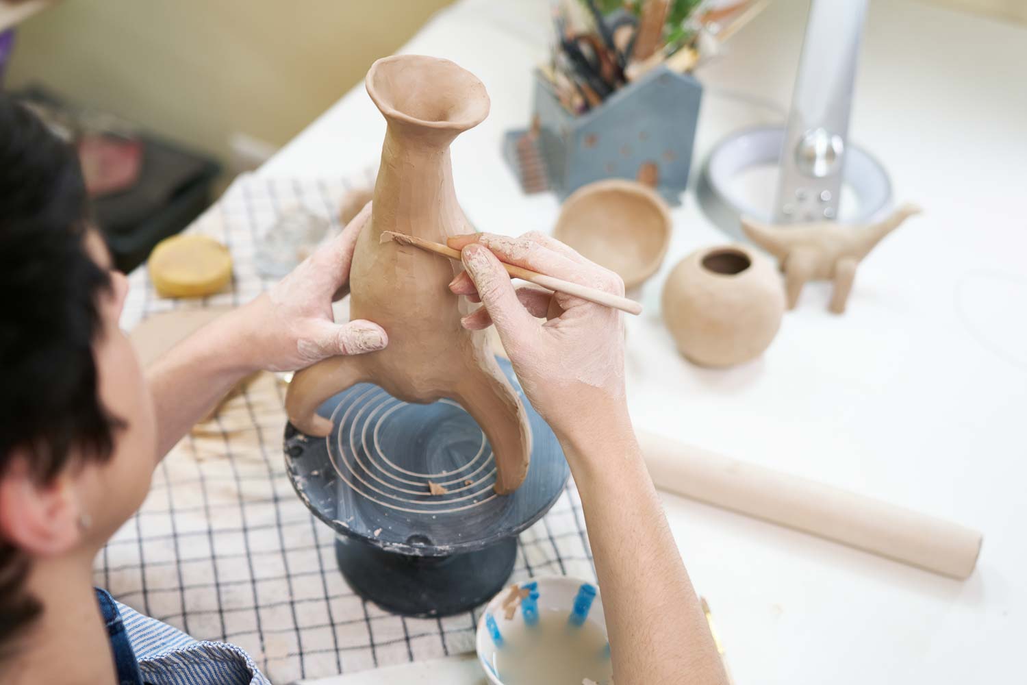 woman sculpts vase from clay by hands closeup artistic studio